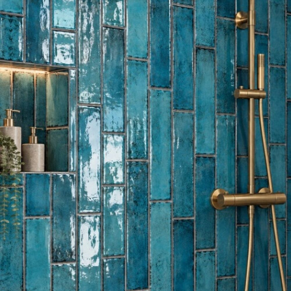 Glanzende turquoise Cifre Alchimia Blue wandtegels in verticaal verspringend verband, met een ingebouwde nis en messing douchekraan.